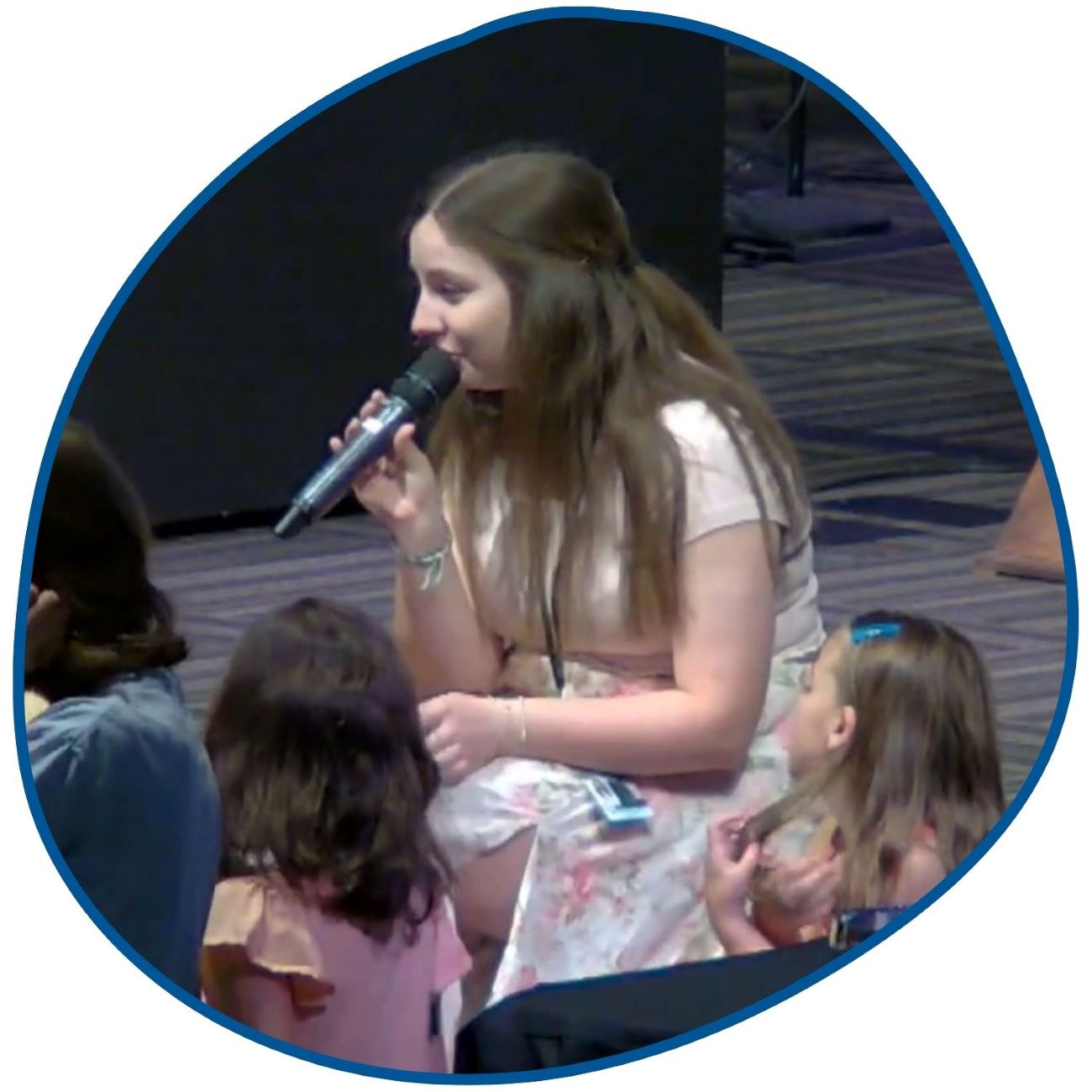 woman singing into microphone surrounded by children