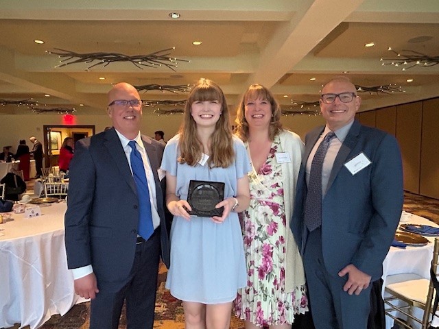 girl holding award with family