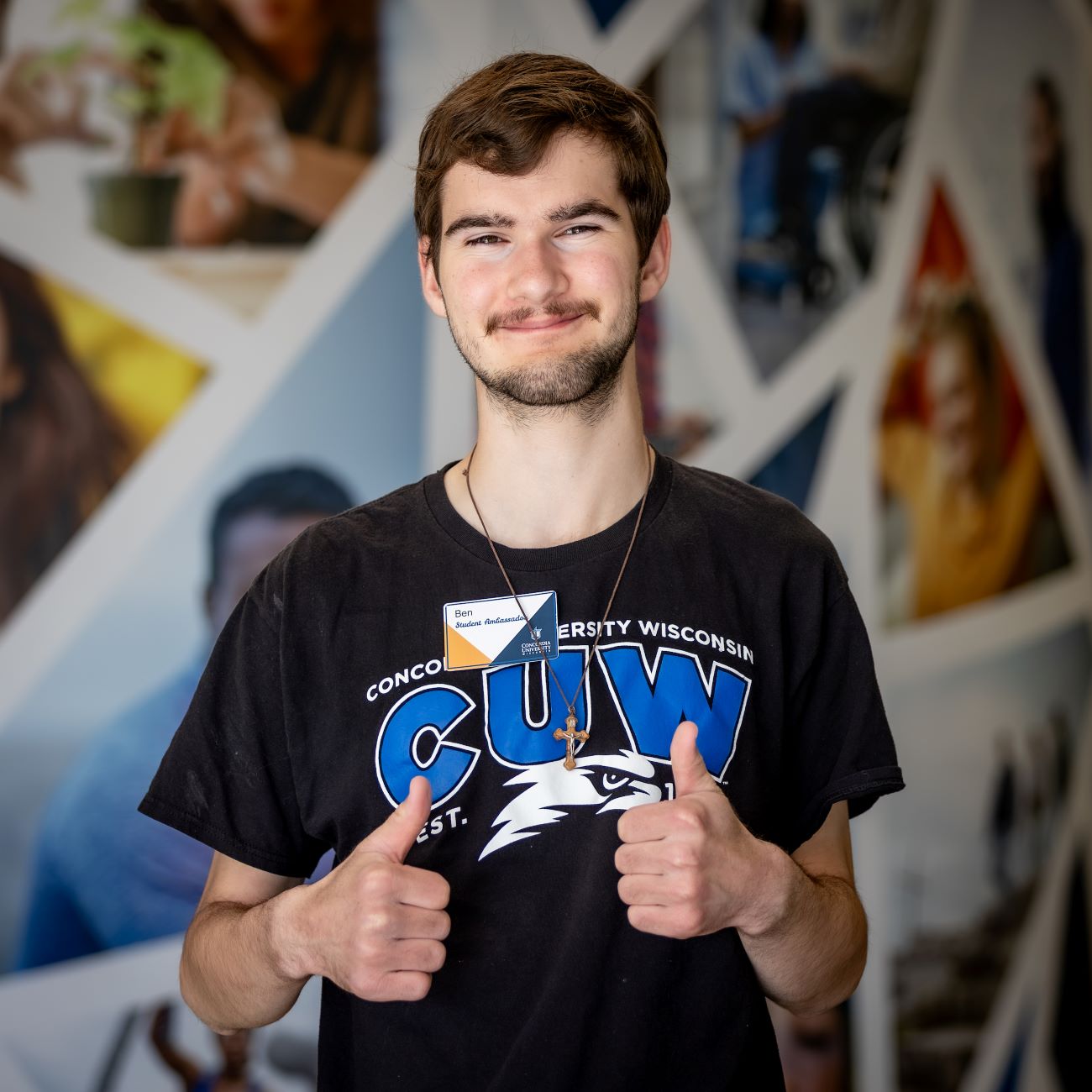 man with dark hair putting his thumbs up