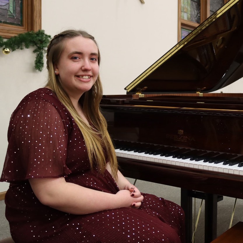 girl in burgundy sitting at piano