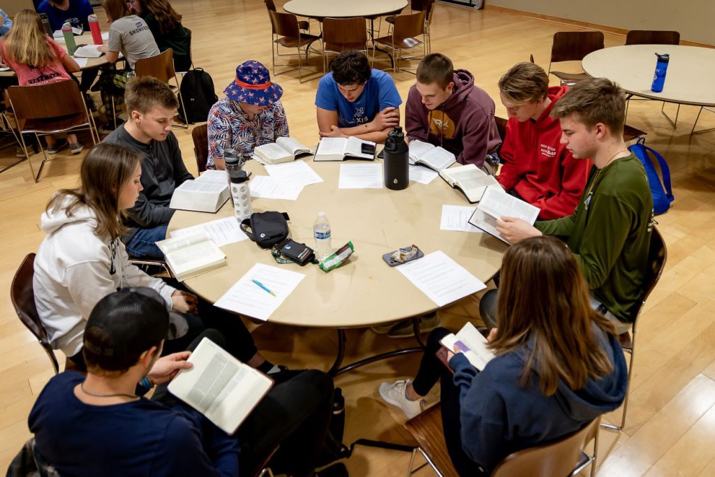 students gathered around bibles at table