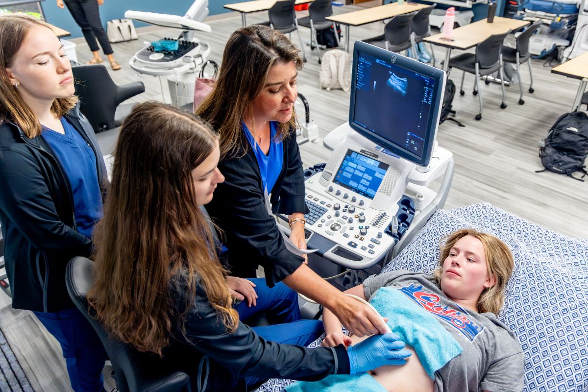 woman laying on table with people using an ultrasound machine