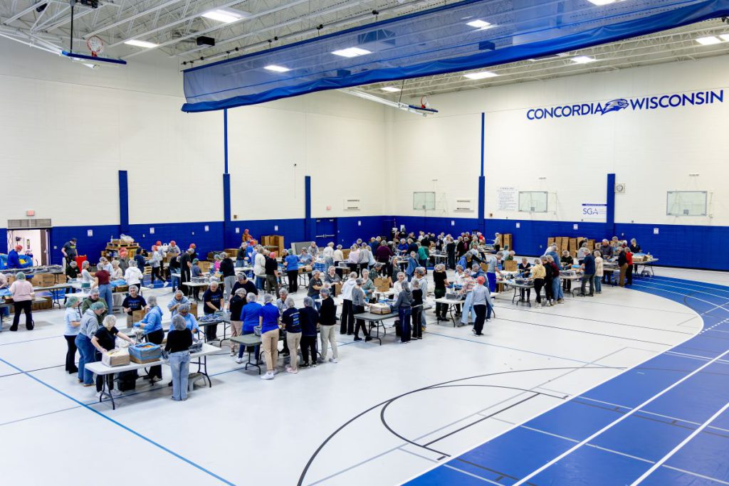 people volunteer to pack food in the gym area