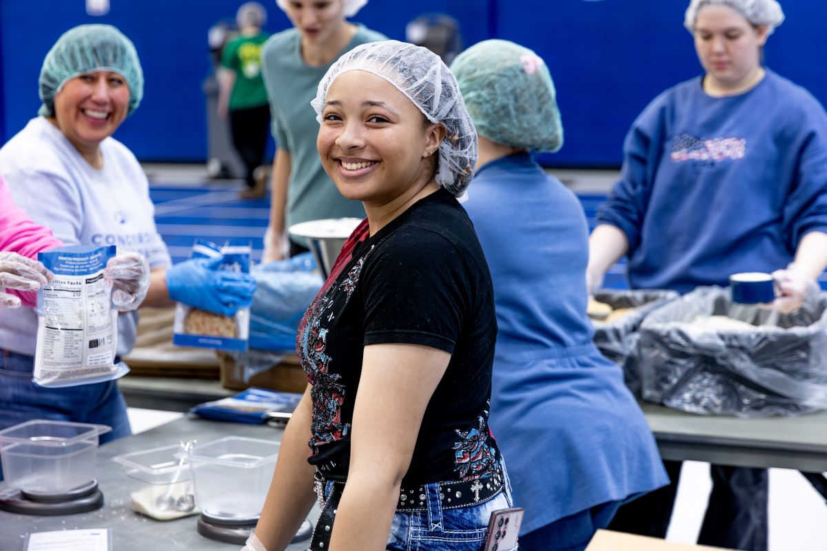 women in black volunteering to pack meals