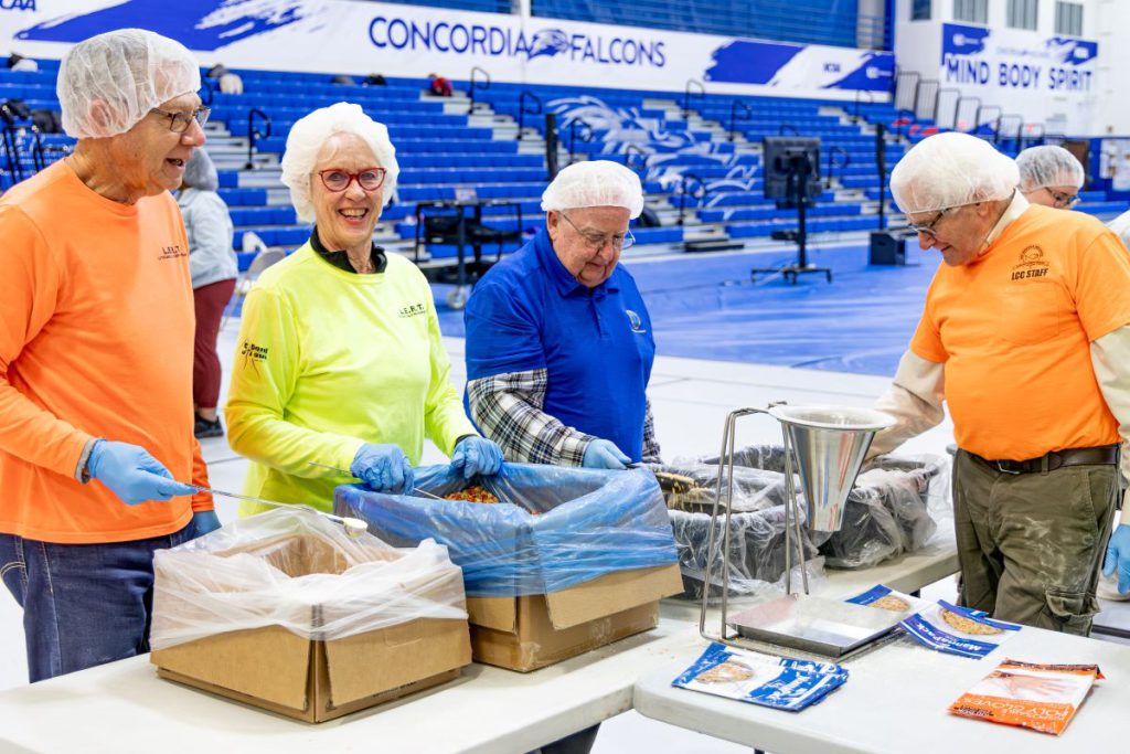 people in bright colored shirts packing meals