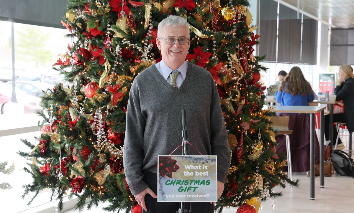 a man speaking in front of Christmas tree