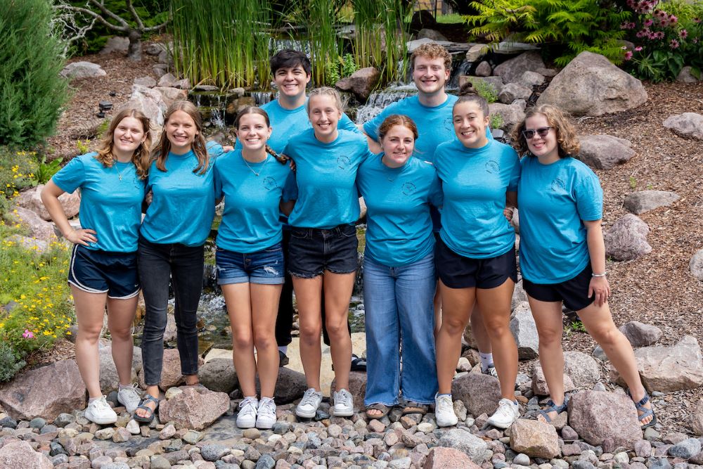group of students with blue shirts on rocks