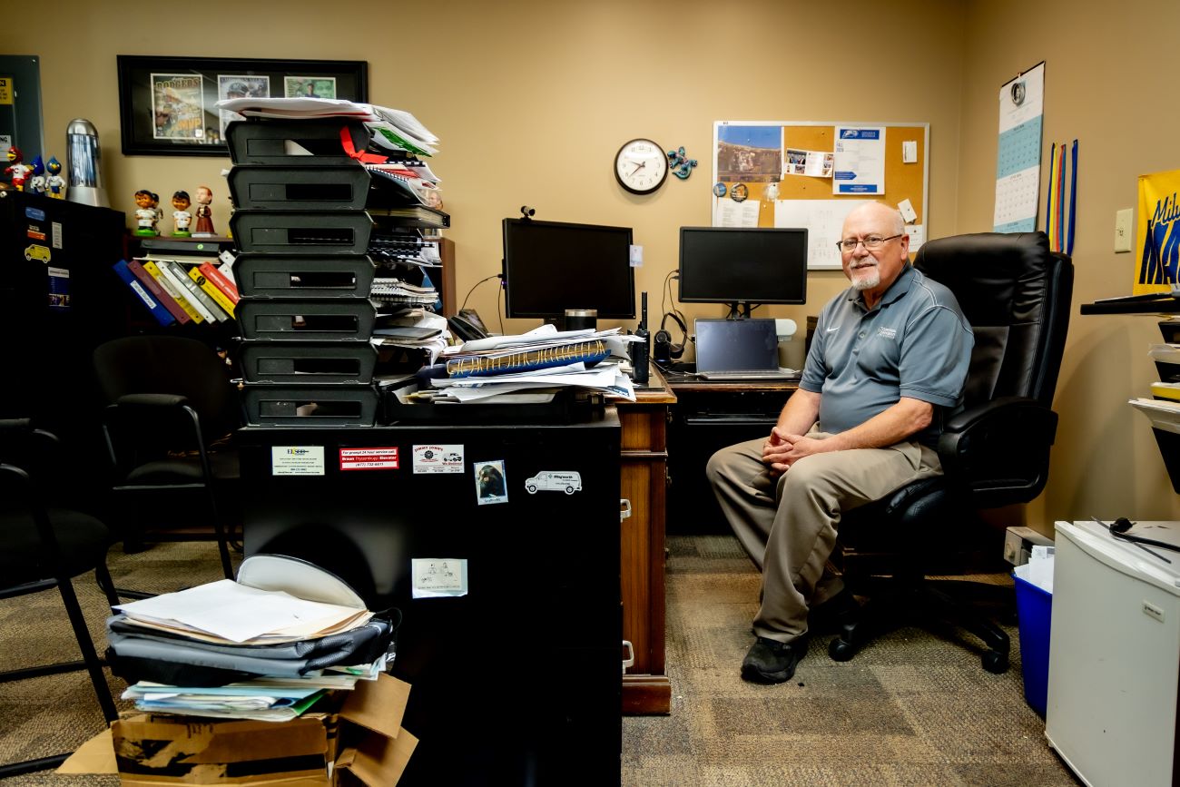 man with gray hair and glasses sitting at his desk