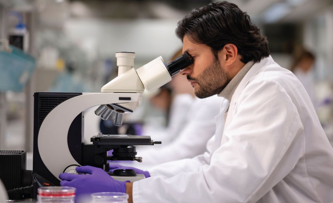 student with white coat and microscope