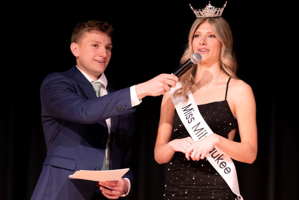 host speaking to judge with crown on her head