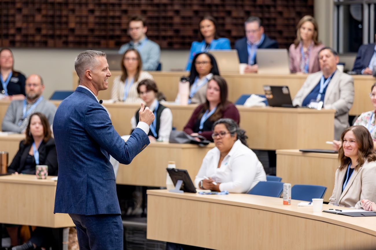 man in blue suit talking to people in rows