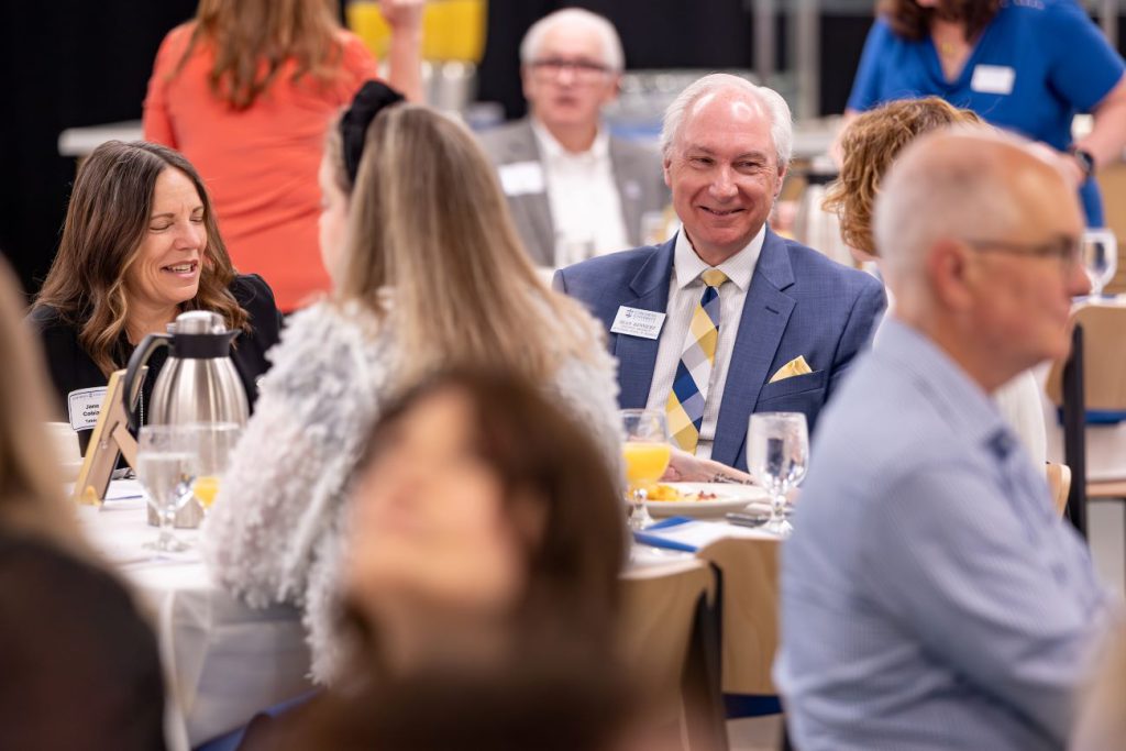 man in blue suit smiling at table