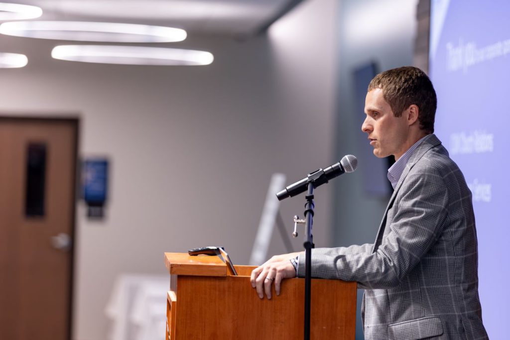sideview of man in gray suit at podium