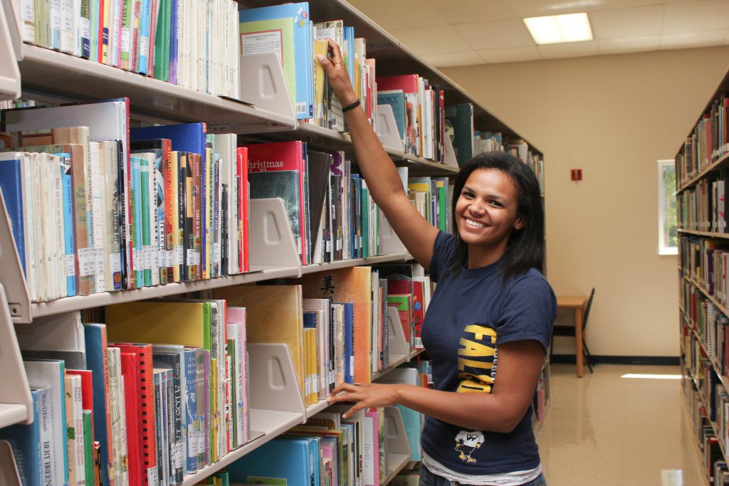 student perusing heles of books in the library