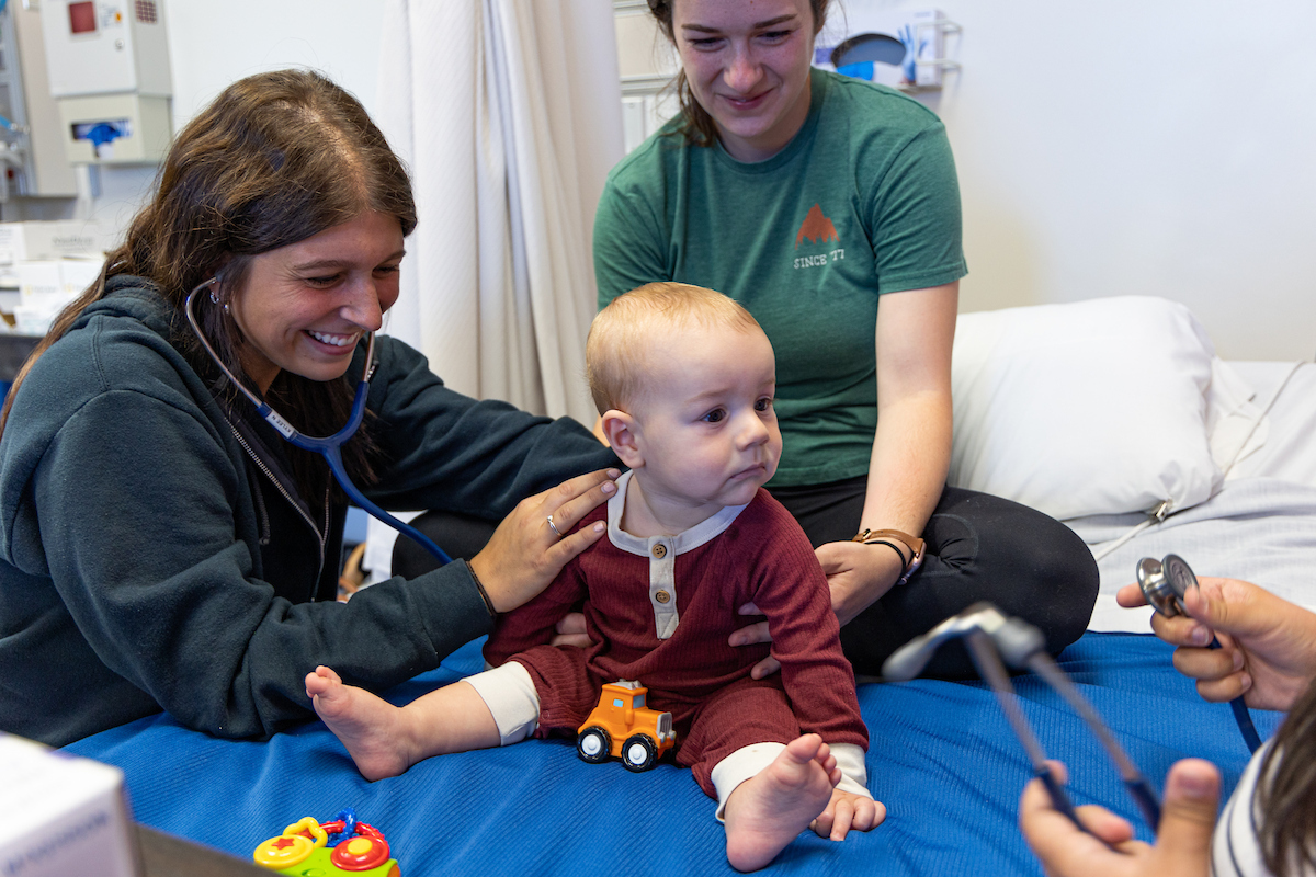 One nursing student working with a baby and its mom on a cot