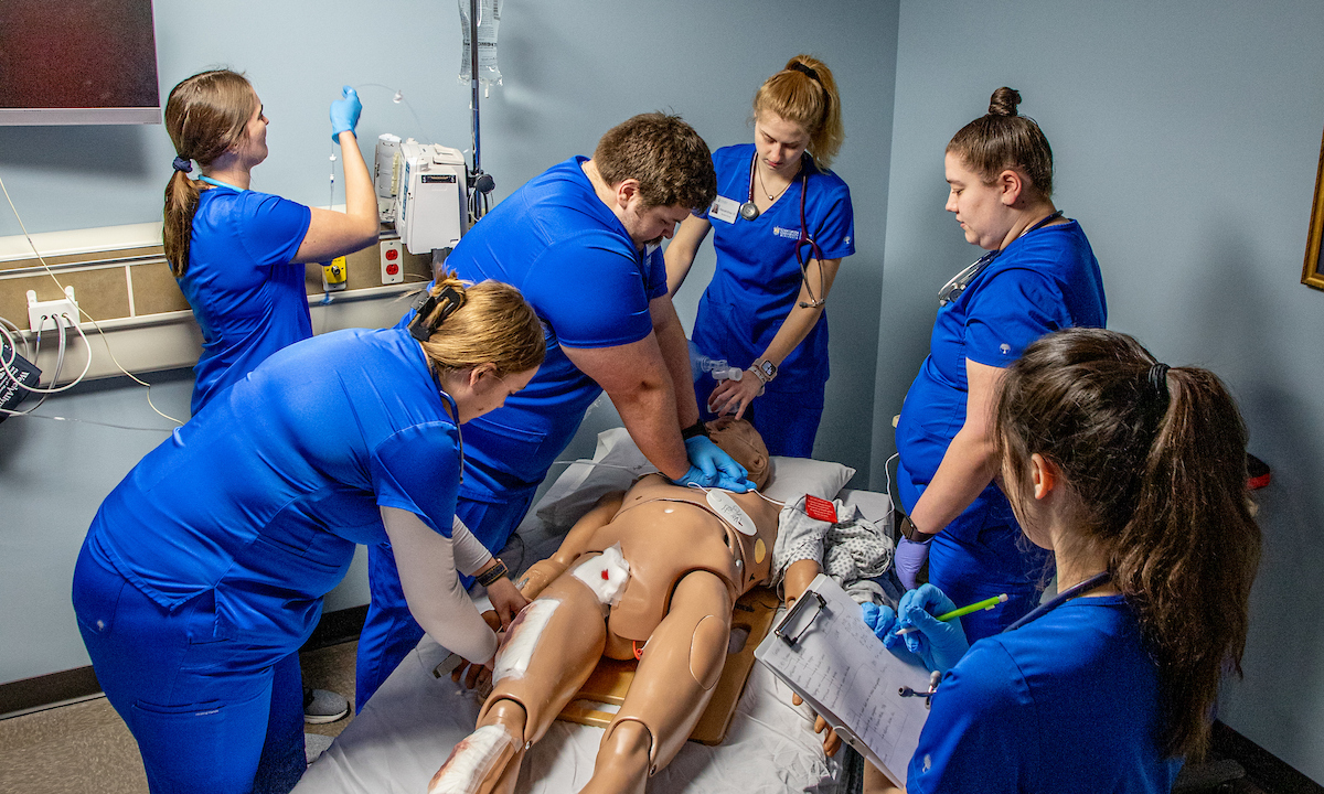 nursing students in blue with dummy