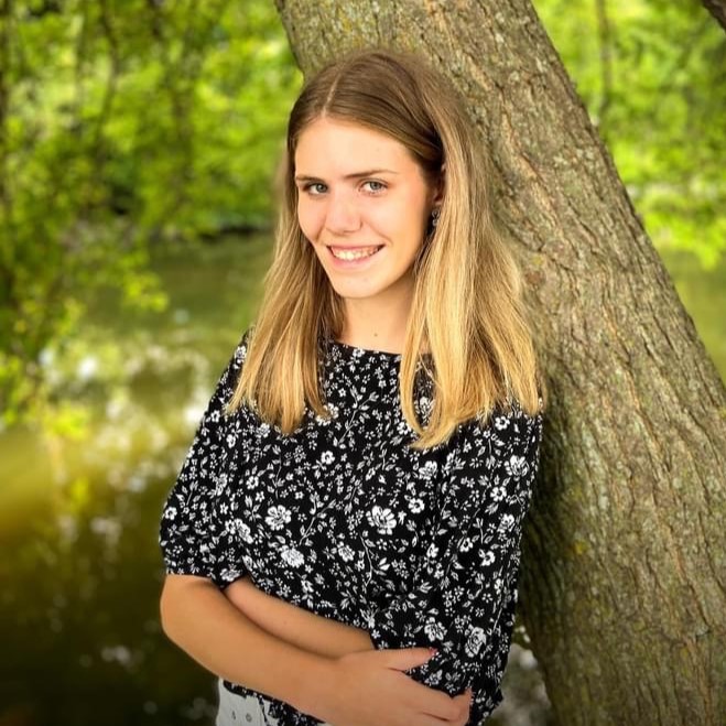 girl leaning on tree with blonde hair