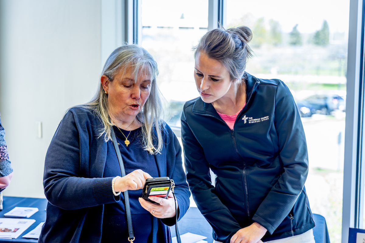 two nurses talking and looking at something in their hands