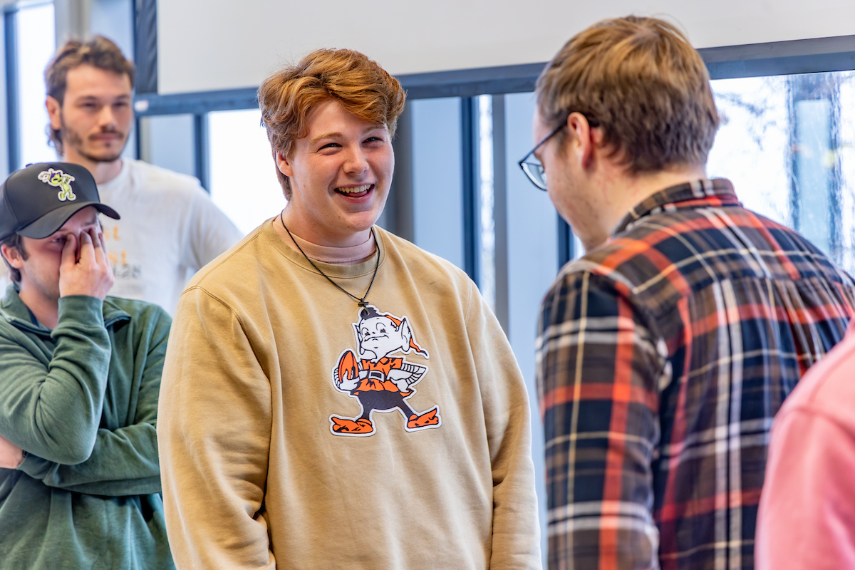 Four male students engage in communication during an exercise at the front of the group.