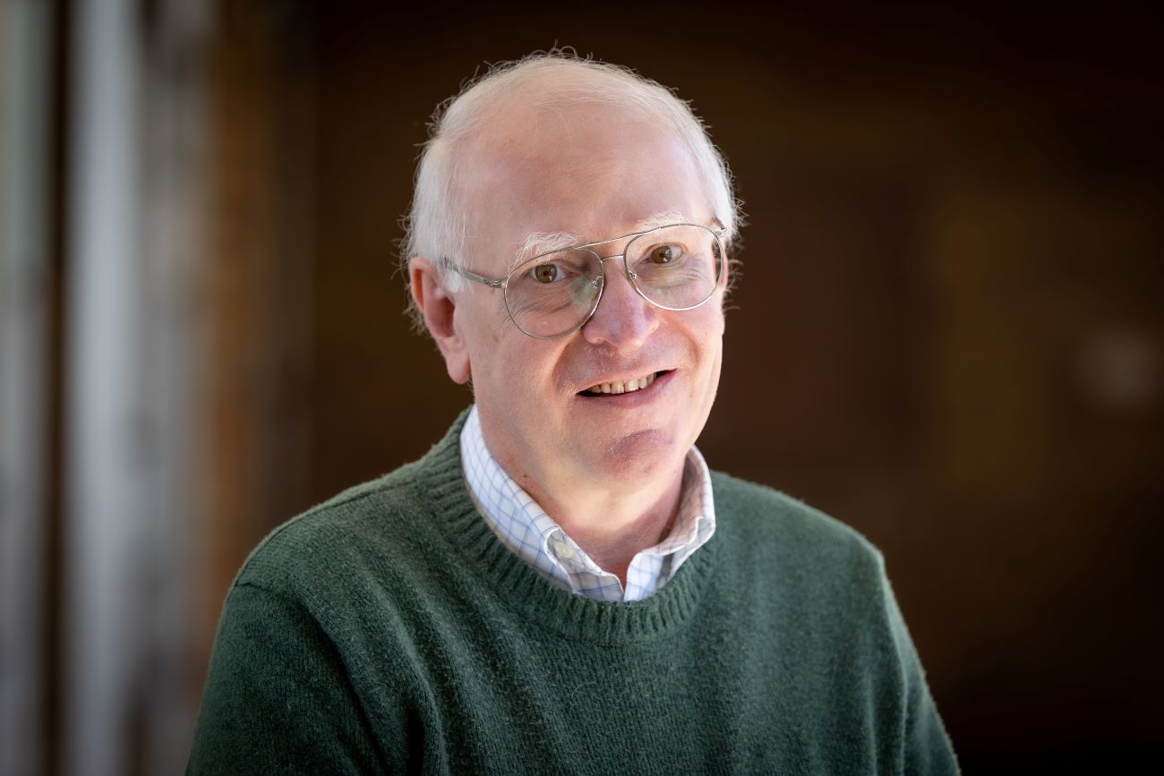man with gray hair and glasses and green sweatshirt