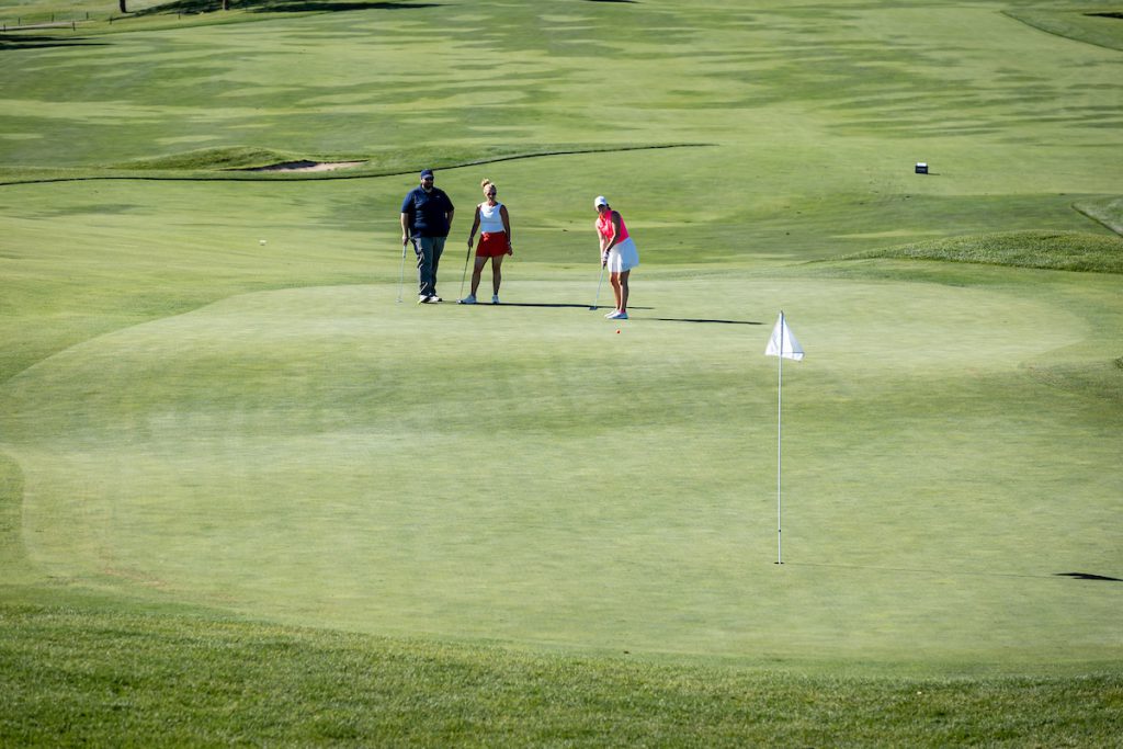 Woman golfing with two other people