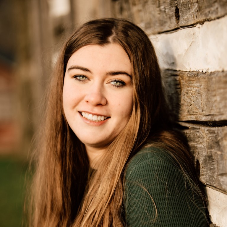 girl with brown hair standing against wall