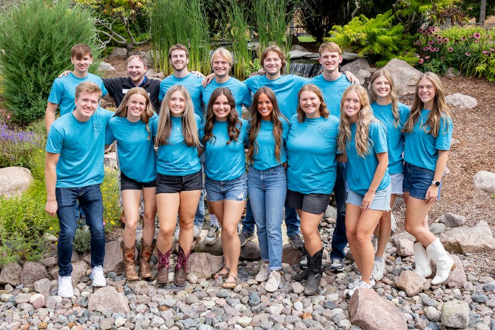 group of students with blue shirts on rocks