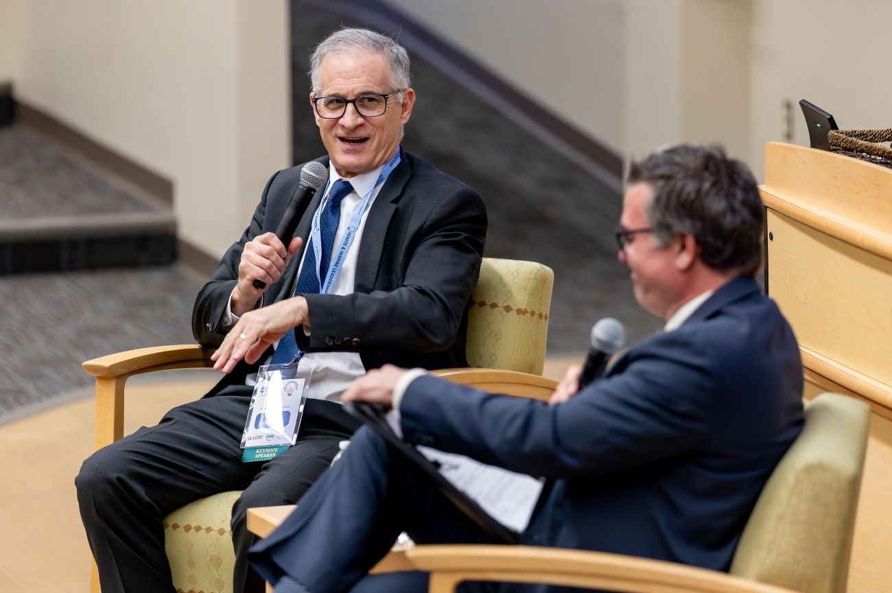 two men in suits talking on stage