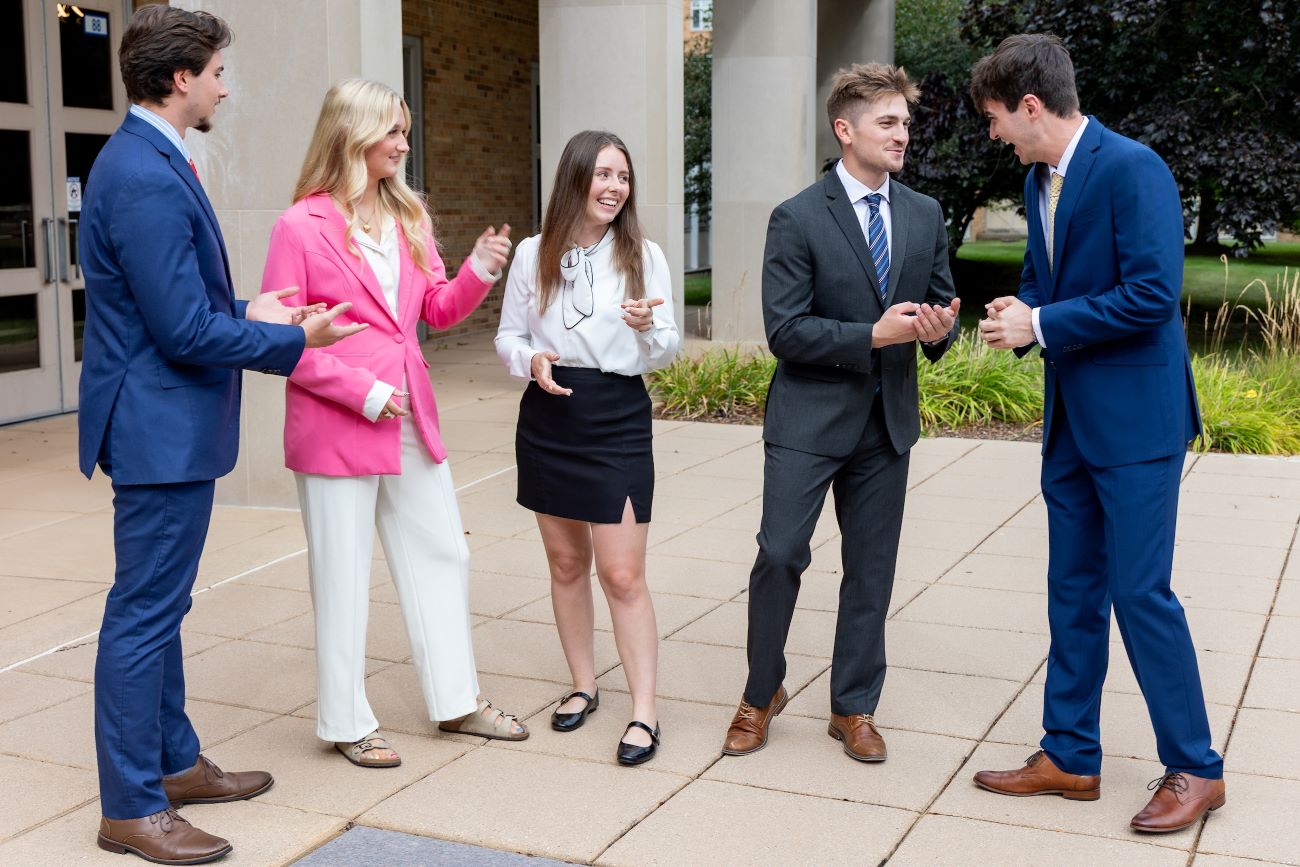 five students conversing outside