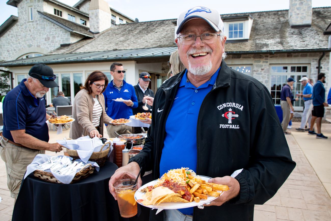 man with glasses and baseball cap holding food