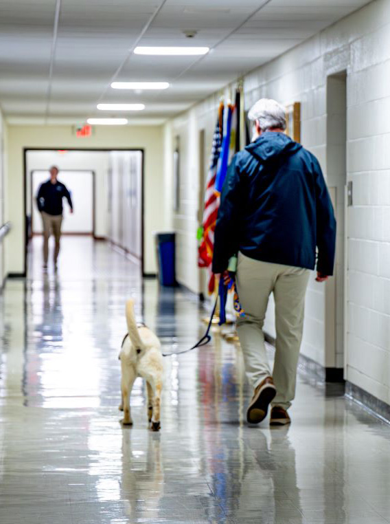 man walking dog down school hallway