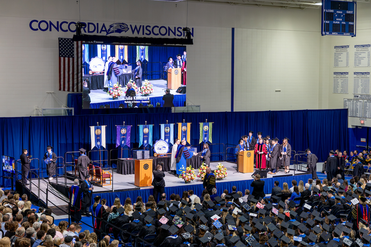 The auditorium filled with graduates in caps and gowns seated together during the commencement ceremony.