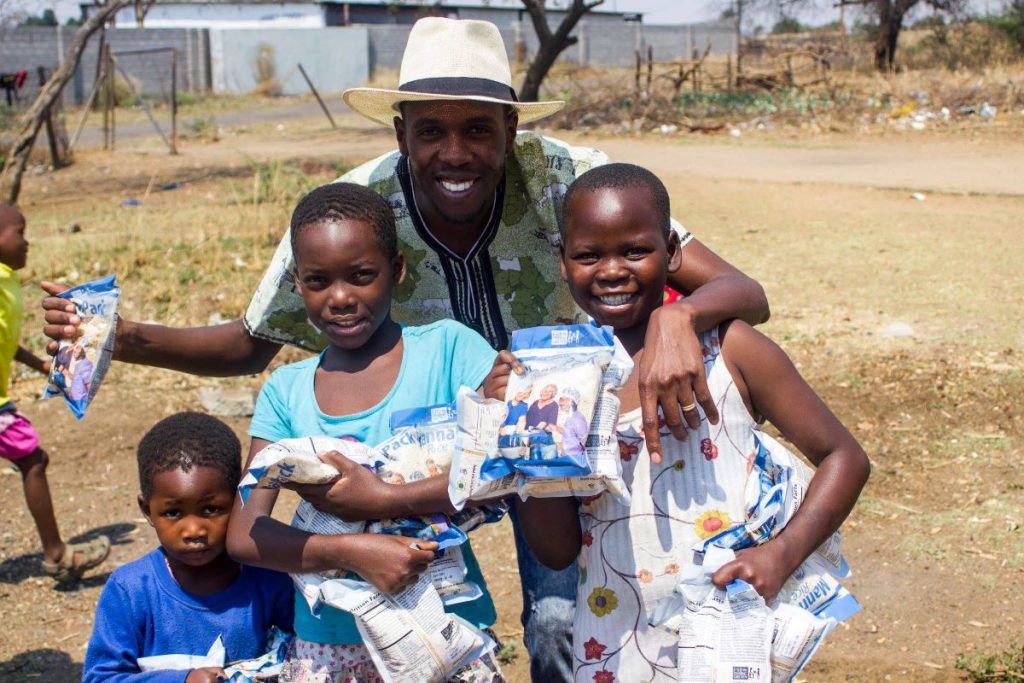 family of four smiling and holding mealpacks