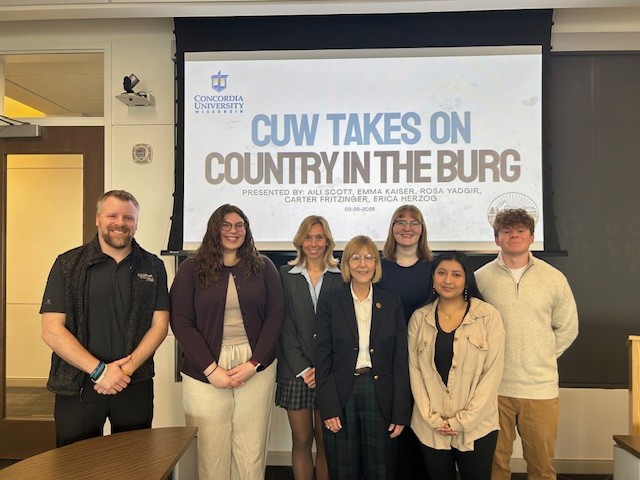 Students and teacher with CEO of Country in the Burg standing in front of a screen