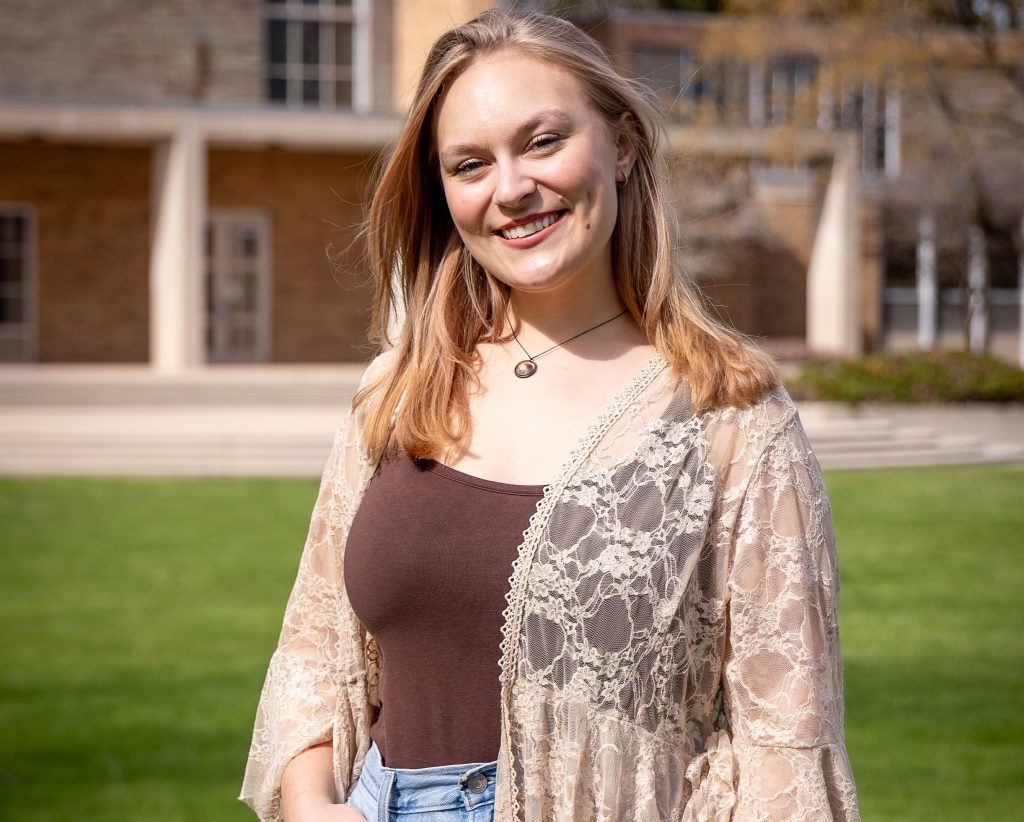 blond haired woman wearing brown and tan standing in front of chapel outside