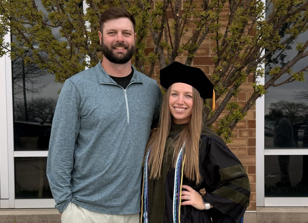 Gracie Wilson in her graduation garb standing next to her husband, Sid.