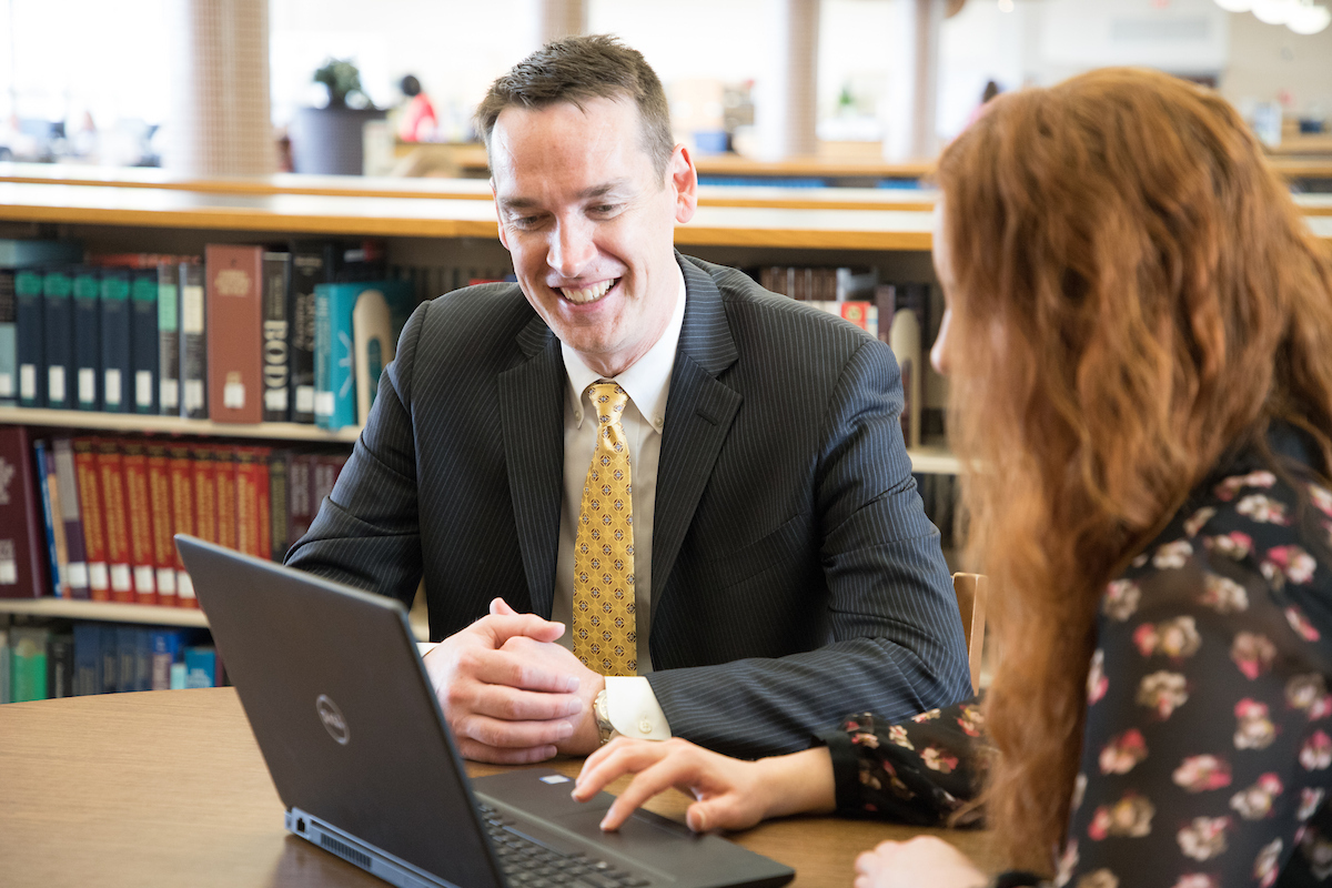 guy in business suit with woman on computer