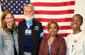 four people standing in front of flag
